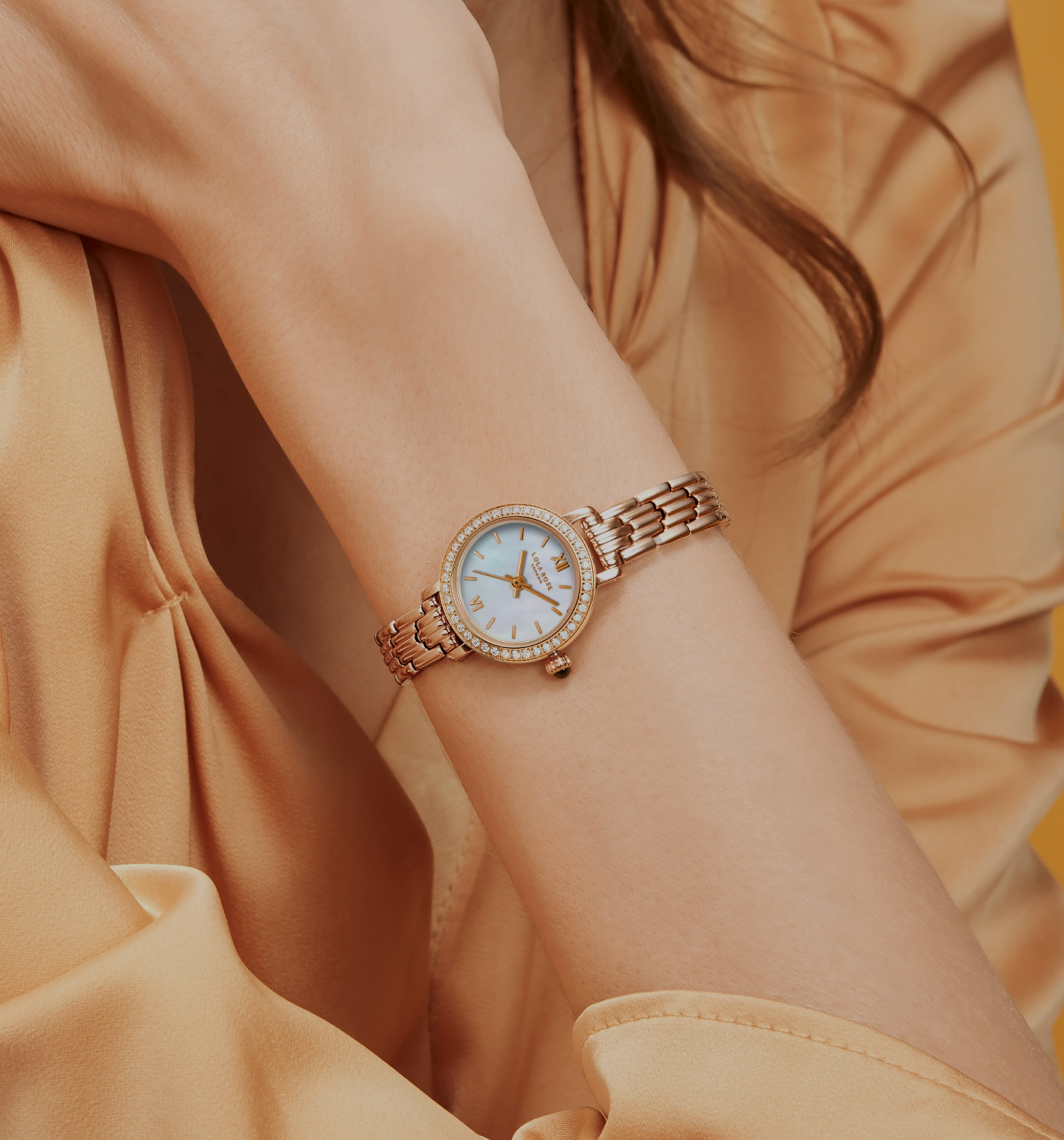 Women’s rose gold watch with white dial worn on wrist